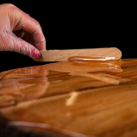 Spreading Crystal Sheen epoxy onto a wooden surface.