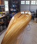 Wooden canoe in a workshop with tools and equipment in the background