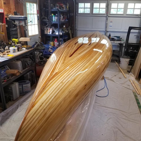 Wooden canoe in a workshop with tools and equipment in the background