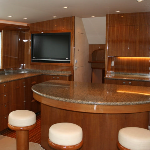 Luxury interior of a yacht with wooden paneling, marble countertop, and television.