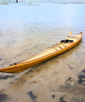 Wooden kayak on a sandy beach with water in the background