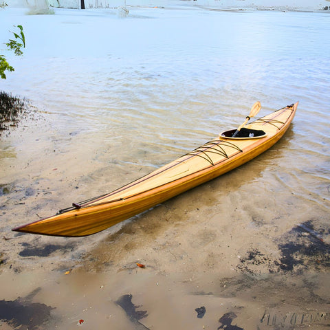 Wooden kayak on a sandy beach with water in the background