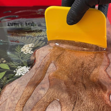 spreading mas table top pro epoxy resin on a wooden board