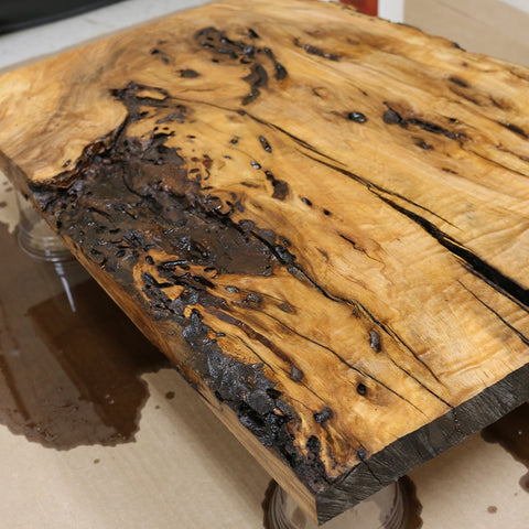 Close-up of a wooden table with a rustic, charred finish.