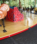 Carousel with wooden horses and a red and black dragon-like creature on a wooden platform.