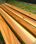 Close-up of a wooden bench with a blurred grass background