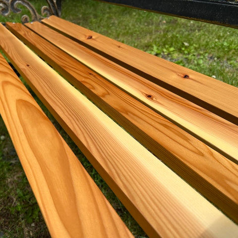 Close-up of a wooden bench with a blurred grass background