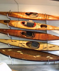Five wooden kayaks of varying lengths mounted on a wall.