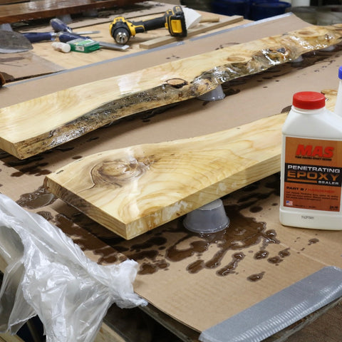 Wooden planks with a bottle of penetrating epoxy on a workbench.