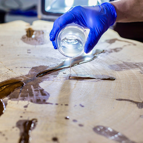Person in blue gloves pouring penetrating epoxy sealer onto a textured surface